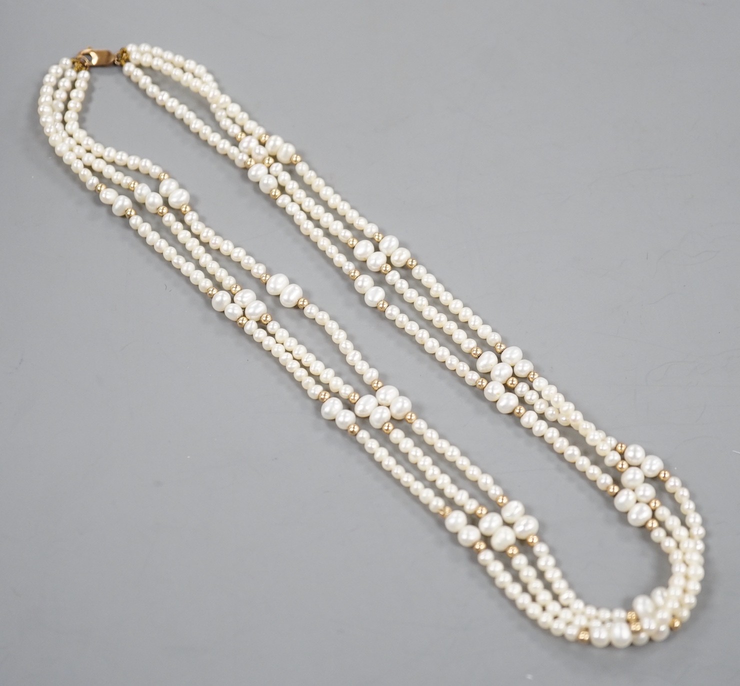 A modern 9k mounted triple strand cultured pearl necklace, 39cm, with yellow metal spacers.